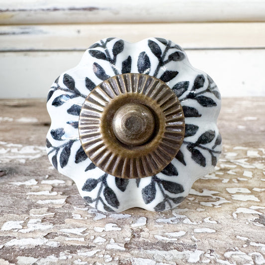Decorative ceramic knob with black leaf pattern and brass center