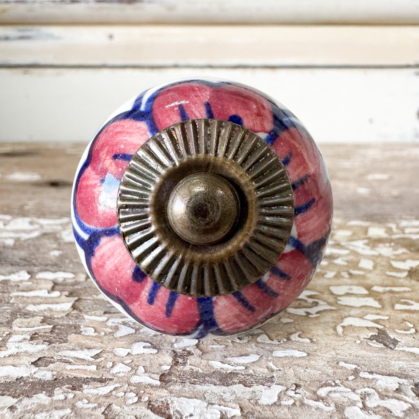 Decorative pink and blue ceramic doorknob with brass centre