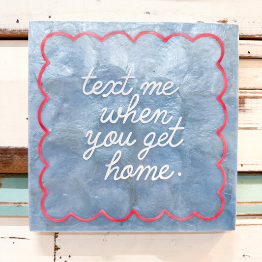 Decorative capiz shell sign with 'text me when you get home' text on a shiny light aqua blue background.