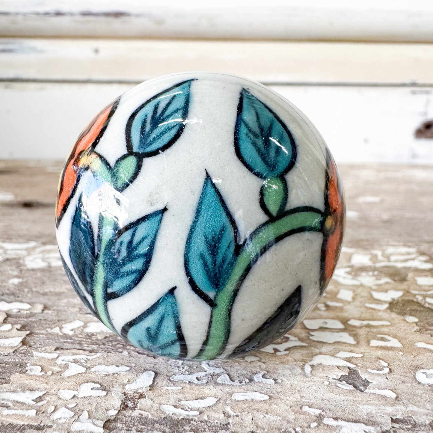 Ceramic knob with leaf design and orange flower