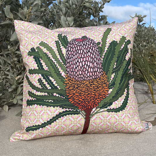 LOST AND FOUND ART CO Banksia 60cm Cushion. Decorative pillow with a floral pattern and central design of a plant, placed outdoors.