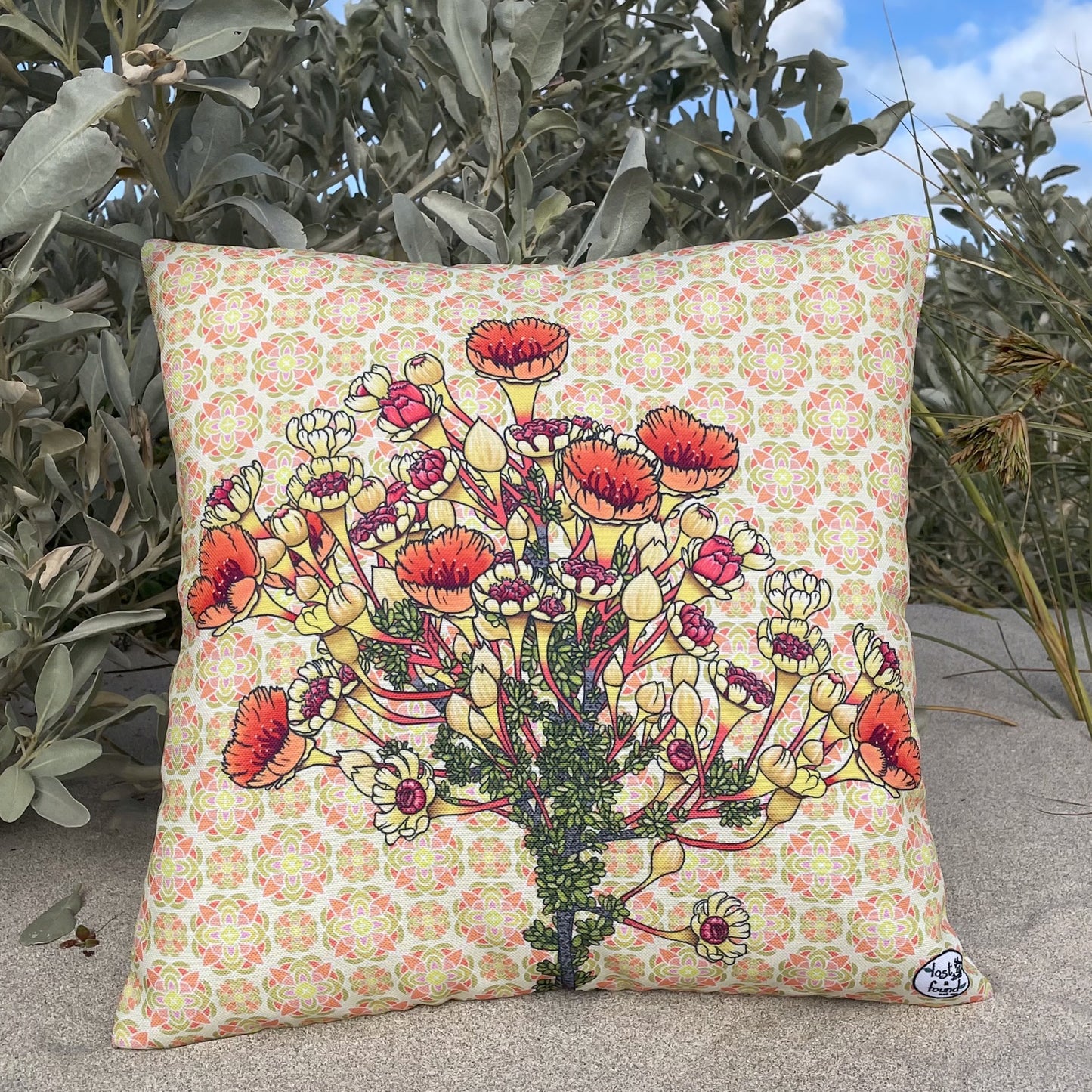 LOST AND FOUND ART CO Coppercups 40cm Cushion. Decorative pillow with floral design on a patterned background, placed outdoors.