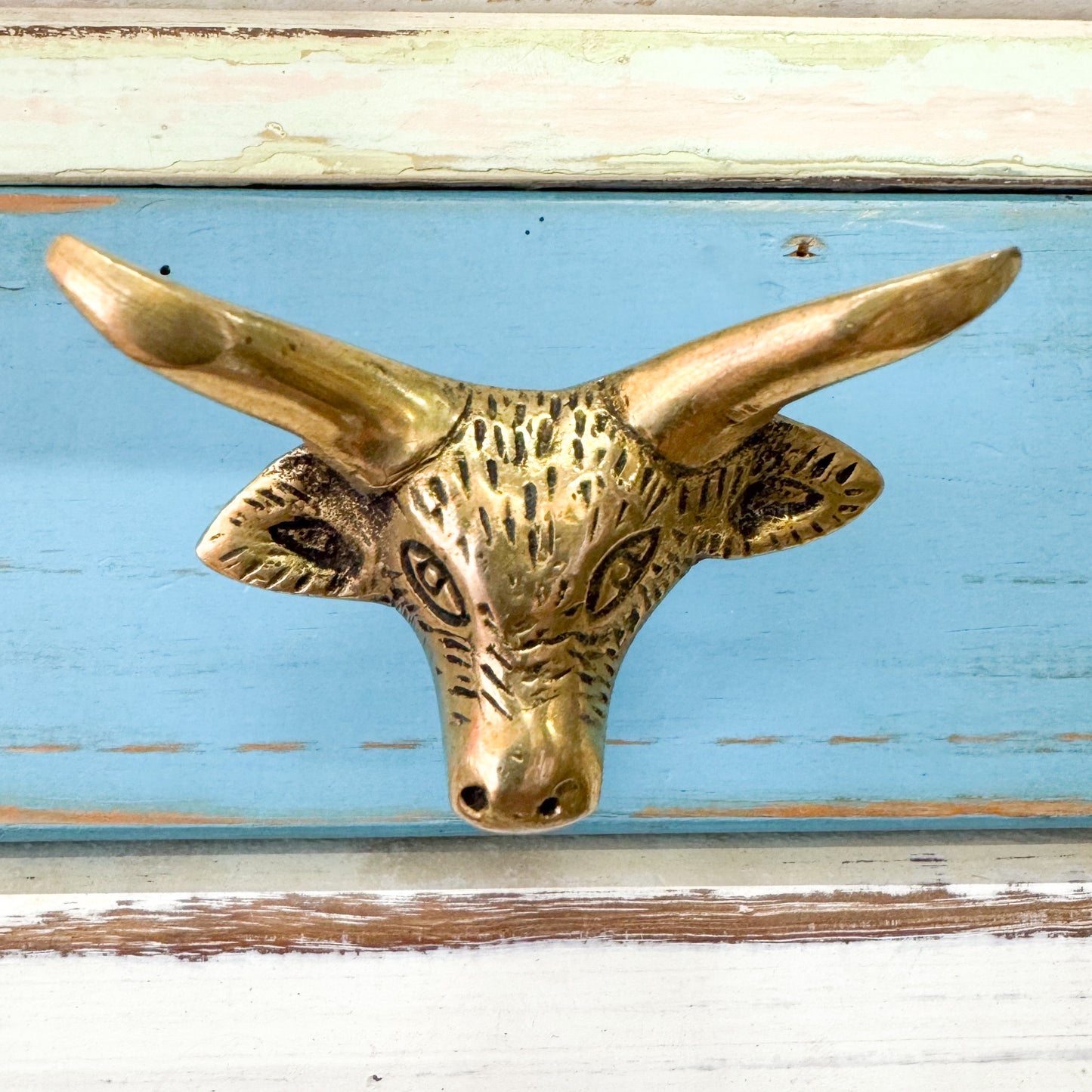 Brass bull head wall hook on a blue and white wooden background