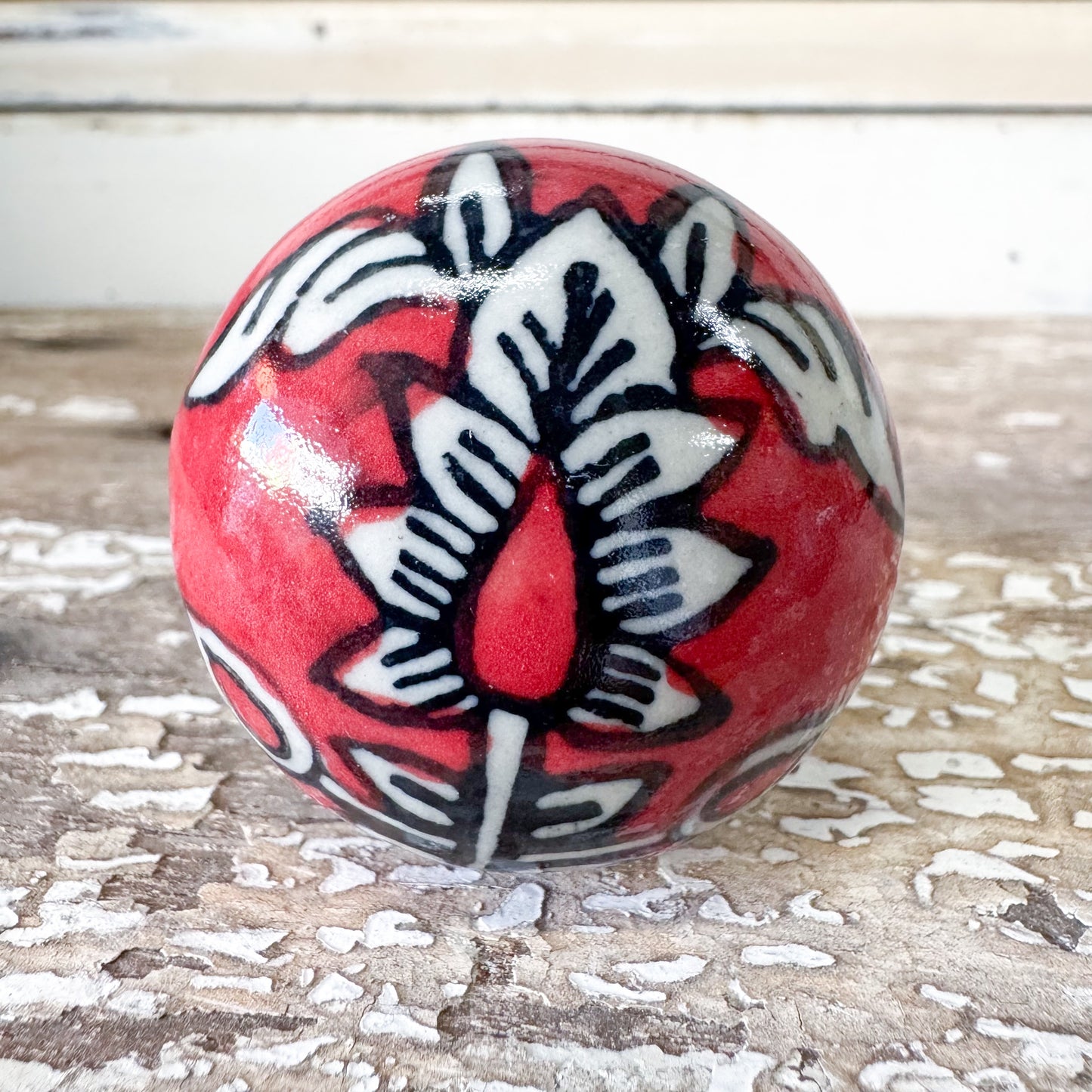 Decorative ceramic doorknob with red, black, and white patterns