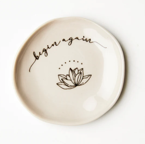 small trinket dish that reads "begin again" with a lotus flower