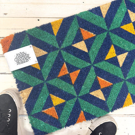 Geometric patterned doormat with colorful triangles by Anna Chandler Design