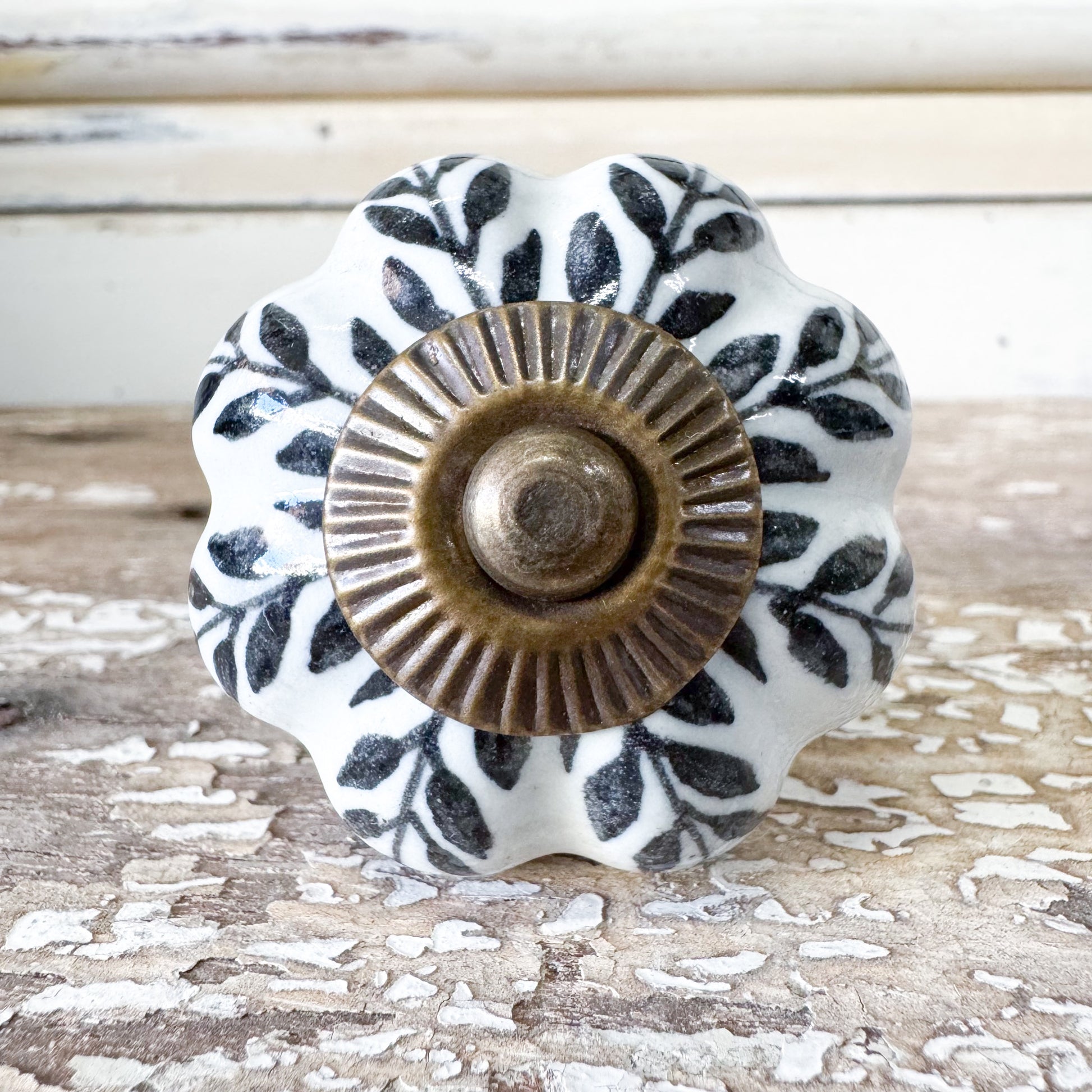 Decorative ceramic knob with black leaf pattern and brass center 
