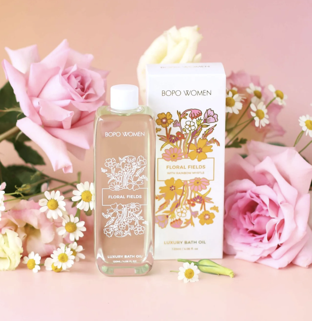 Bath oil bottle and packaging with floral design on a pink background