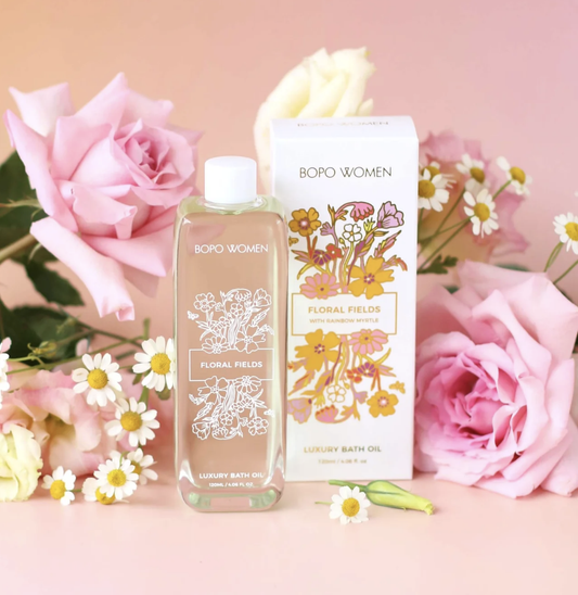 Bath oil bottle and packaging with floral design on a pink background