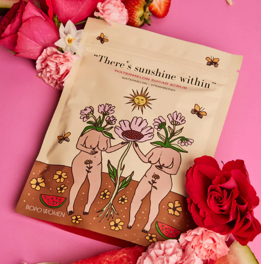 A package of Watermelon Sugar Scrub by Bopo Women, surrounded by pink flowers and citrus fruits, with a graphic design featuring two figures and plants.