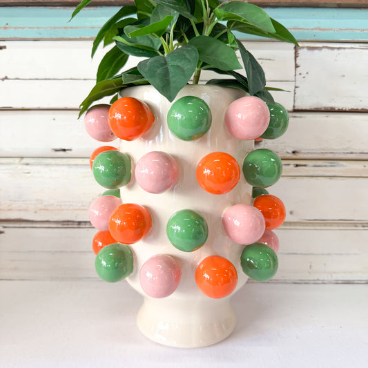 Decorative vase with colorful spherical ornaments on a wooden surface