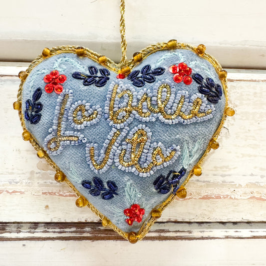 Heart-shaped embroidered decoration with floral designs and 'La Dolce Vita' text 