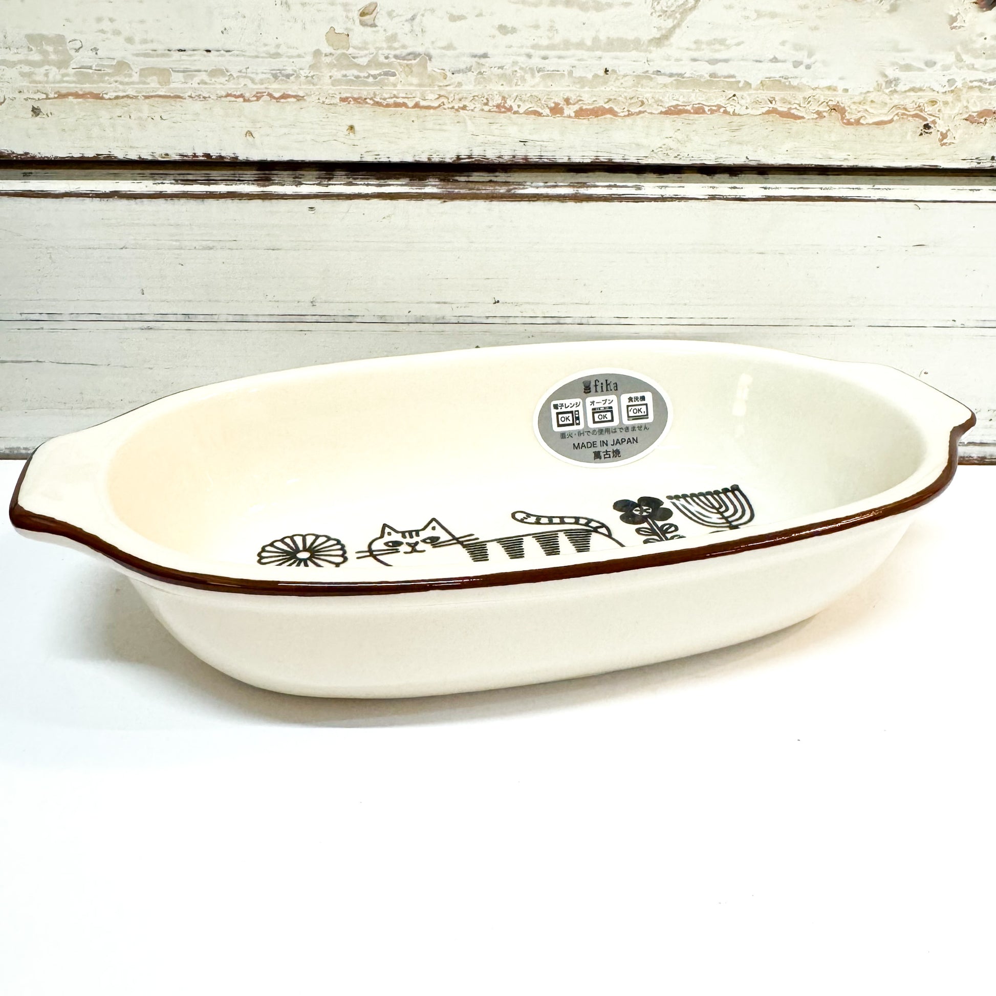 White ceramic dish with brown rim and cat illustrations on a white background