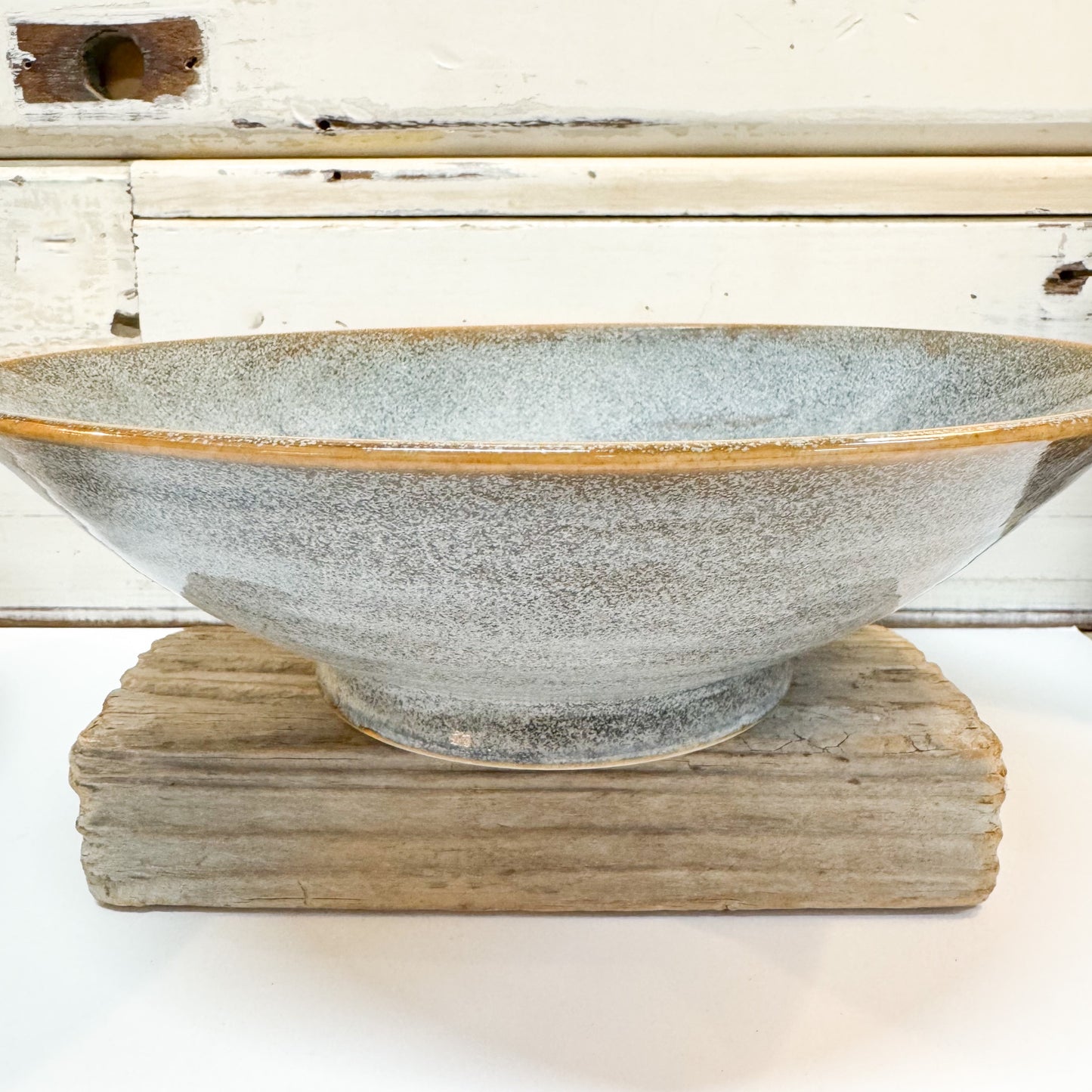 Ceramic bowl with textured surface on a wooden stand against a rustic wooden background