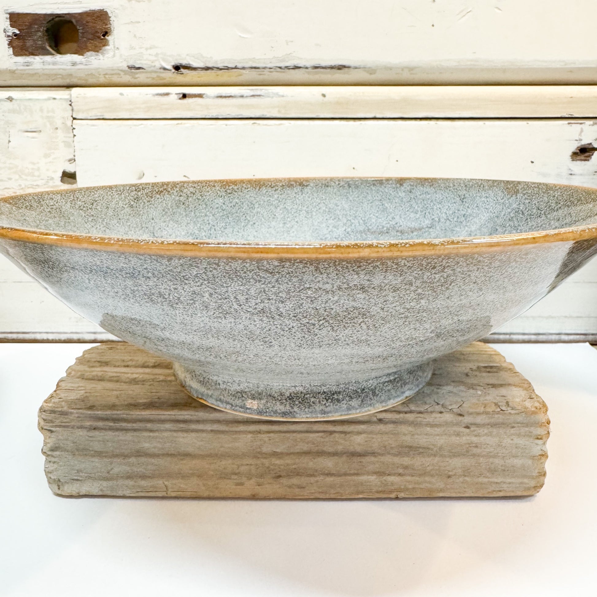 Ceramic bowl with textured surface on a wooden stand against a rustic wooden background