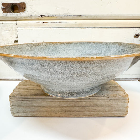 Ceramic bowl with textured surface on a wooden stand against a rustic wooden background