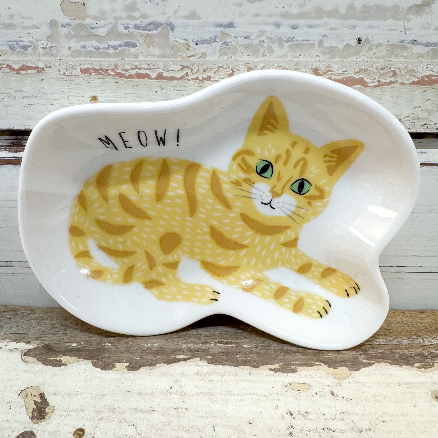 Concept Japan | Ginger Cat Dish
A white ceramic cat-shaped dish featuring a yellow tabby cat illustration and the word 'MEOW!' in black text, set against a rustic distressed wood background.