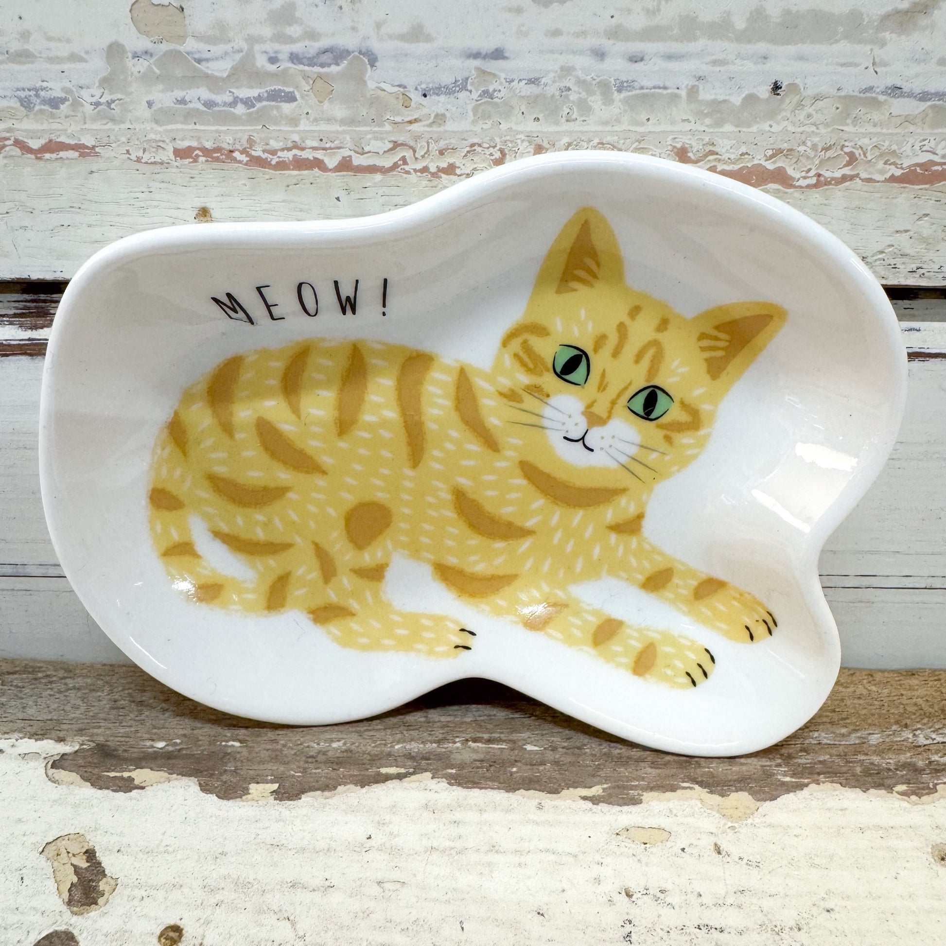 Concept Japan | Ginger Cat Dish
A white ceramic cat-shaped dish featuring a yellow tabby cat illustration and the word 'MEOW!' in black text, set against a rustic distressed wood background.