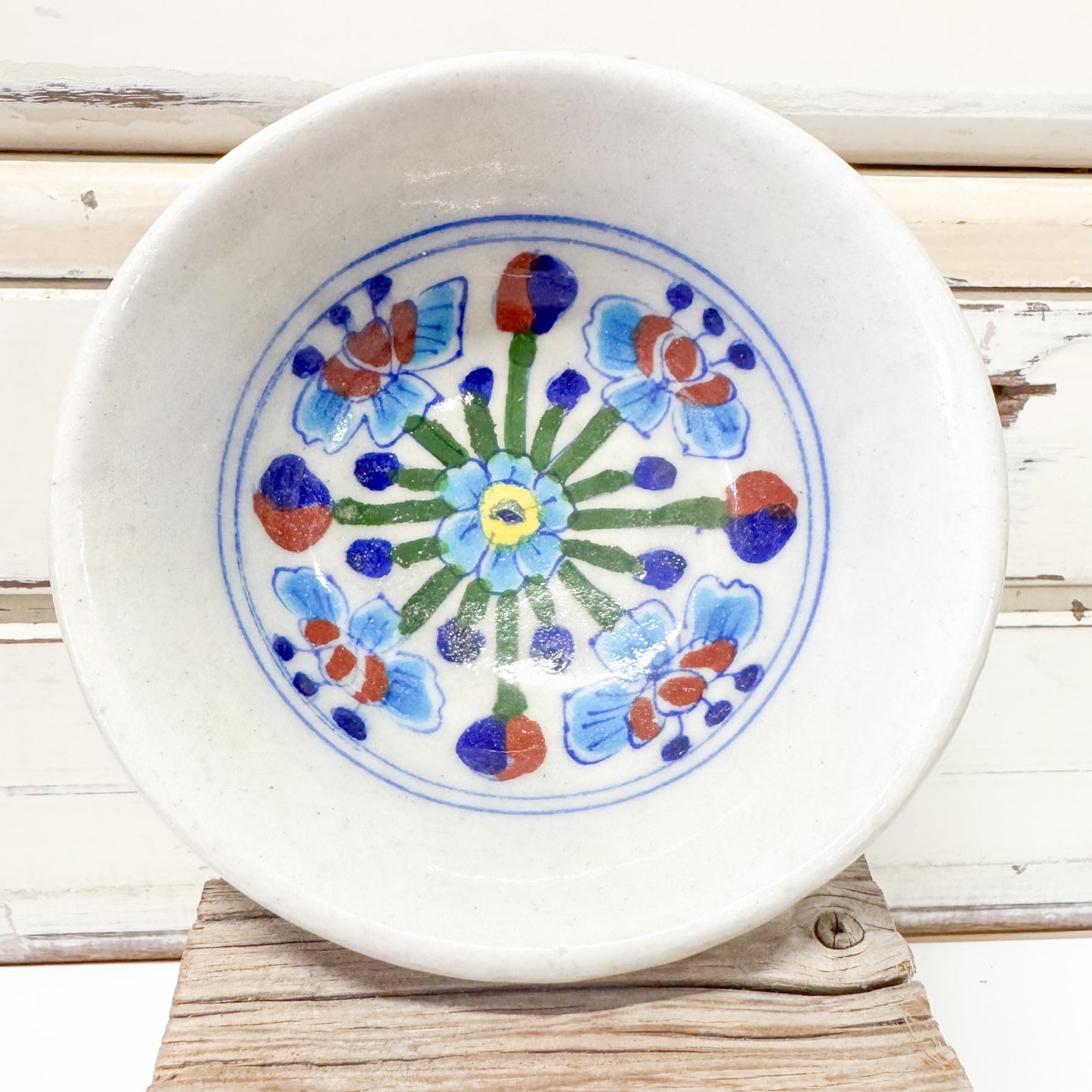 Indian Ceramics - Himalayan Blue Bowl 10cm. Ceramic plate with floral design on a wooden surface