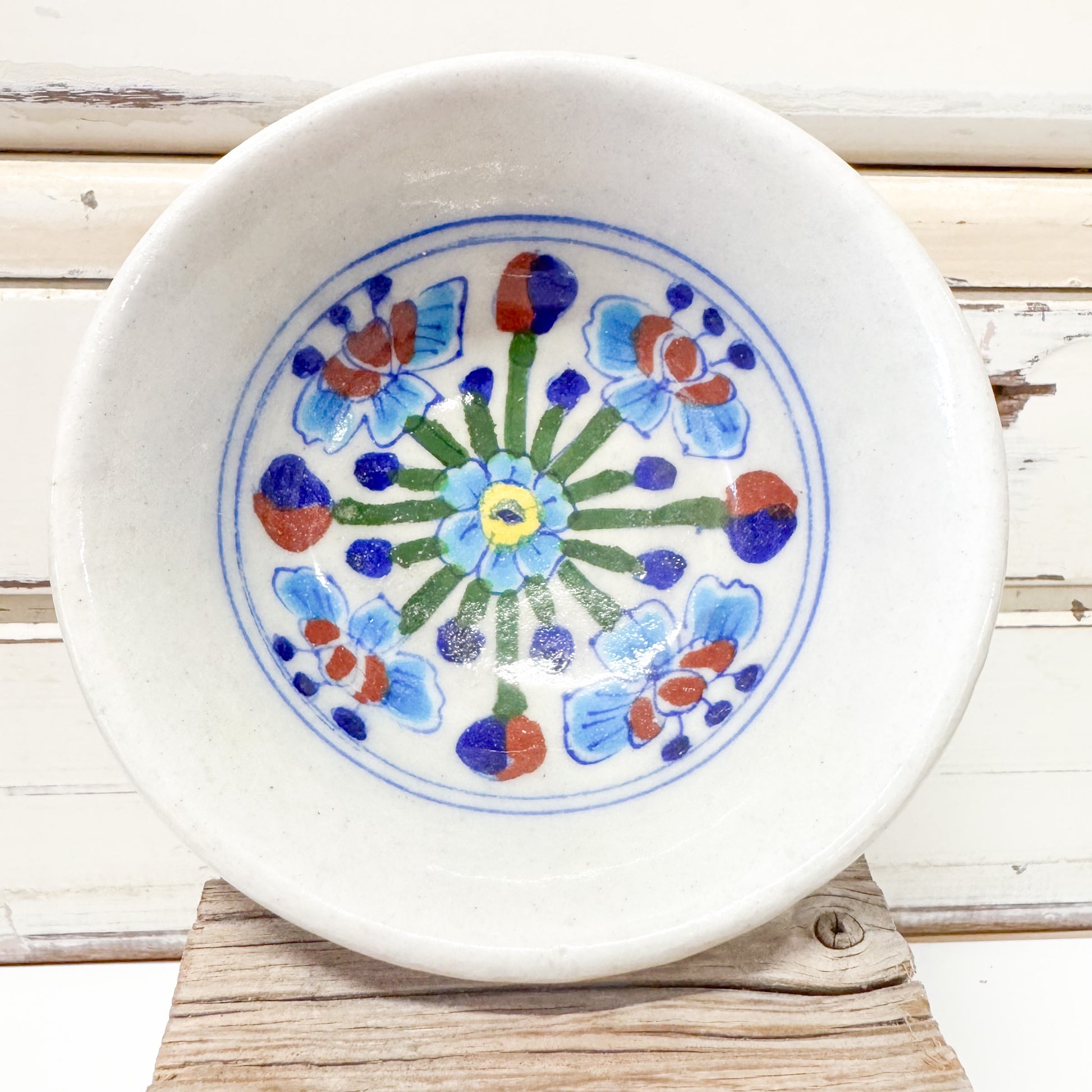 Indian Ceramics - Himalayan Blue Bowl 10cm. Ceramic plate with floral design on a wooden surface