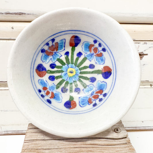 Indian Ceramics - Himalayan Blue Bowl 10cm. Ceramic plate with floral design on a wooden surface