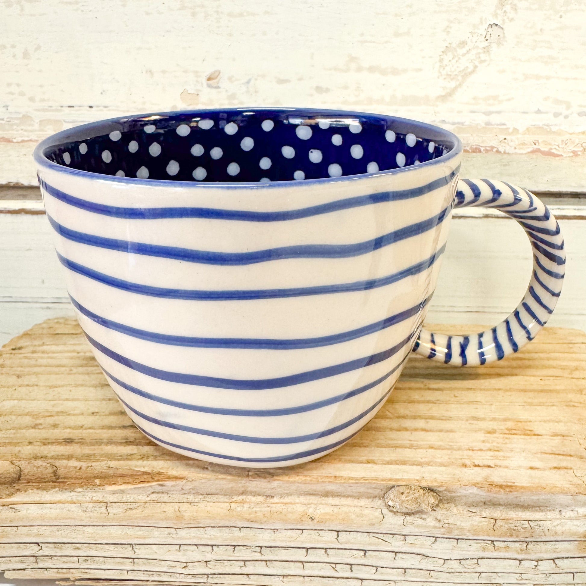 Ceramic mug with blue and white polka dot interior and striped exterior 