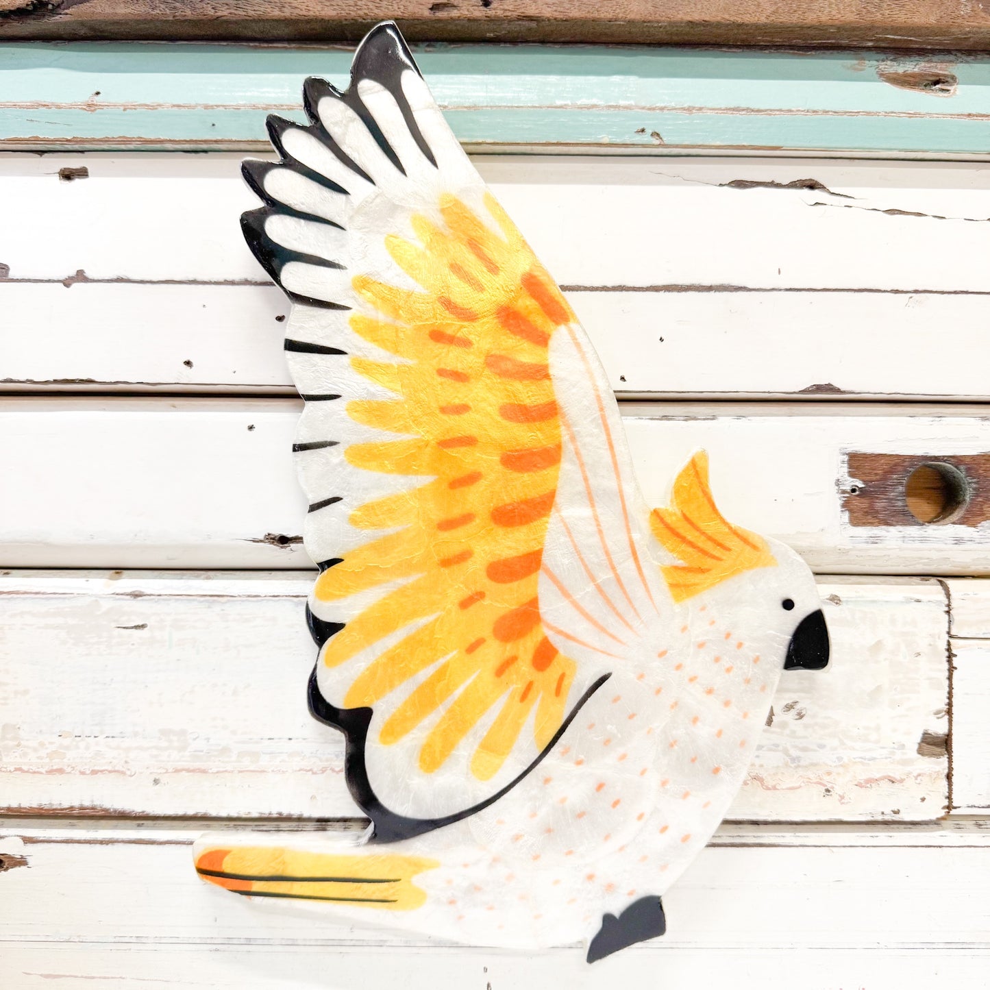 Hand-painted glossy Capiz shell wall tile in the shape of a cockatoo with white, yellow, and black colours... Jones & Co - Aerial Cockatoo