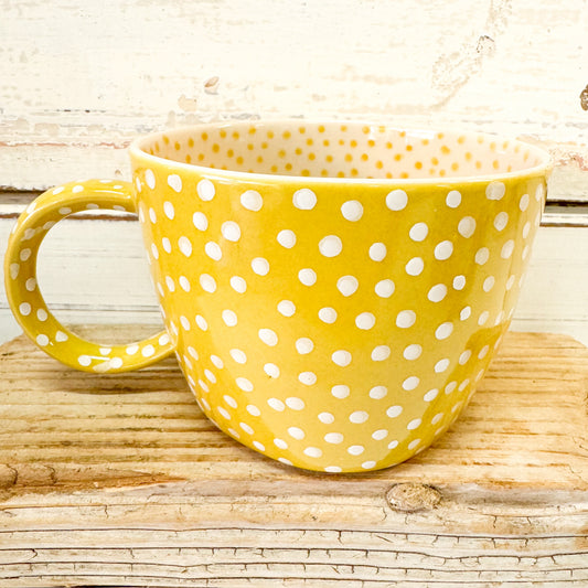 Yellow mug with white polka dots on a wooden surface