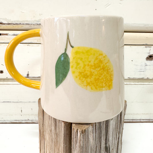 White mug with yellow lemon design on a wooden block against a rustic wooden background