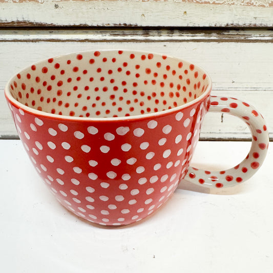 Jones & Co | Chino Mug - Red Spot 
A ceramic mug with a red and white polka dot pattern, shown from a front angle against a rustic white wooden background.