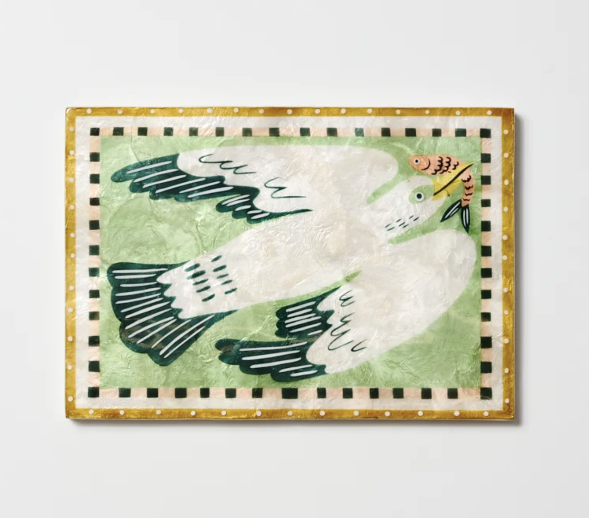 A square decorative capiz shell tile featuring a stylized white dove with dark green wings on a pale green background, surrounded by a gold and black checkered border. The dove also holds a small orange fish in its beak.