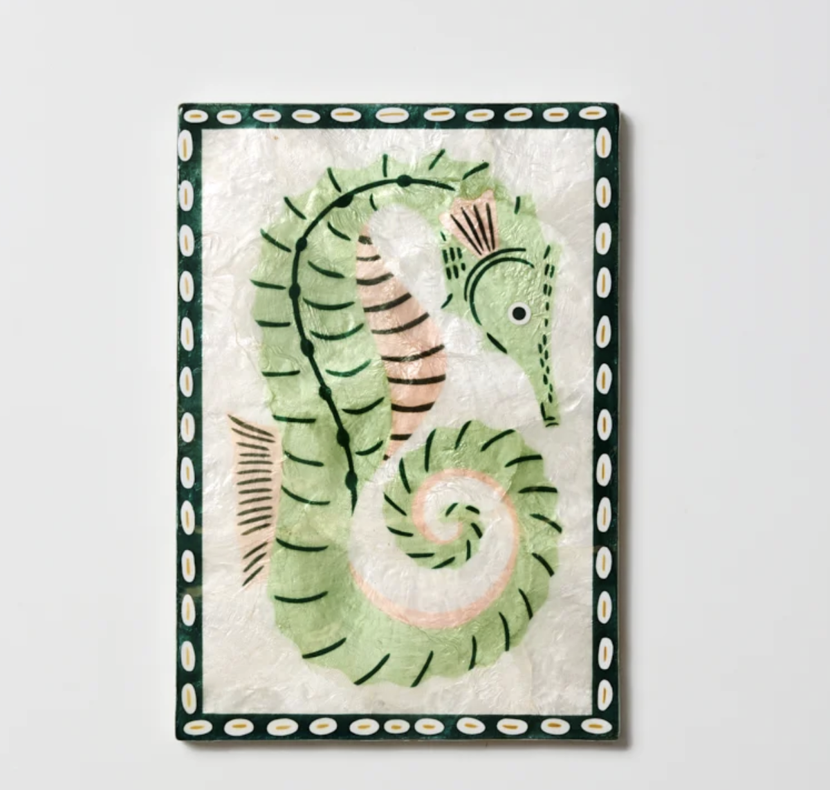 A framed wall art piece featuring a stylized seahorse illustration. The artwork has a pale green seahorse with black linework and soft peach accents on a textured off-white background, surrounded by a dark green border with white oval motifs.