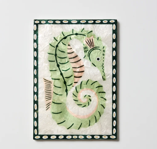 A framed wall art piece featuring a stylized seahorse illustration. The artwork has a pale green seahorse with black linework and soft peach accents on a textured off-white background, surrounded by a dark green border with white oval motifs.