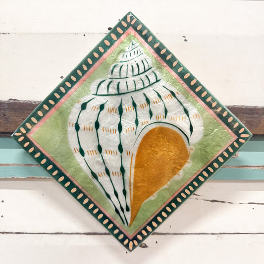 A square decorative capiz wall tile with rounded corners, featuring a painted seashell motif. The tile has a dark green border with small gold dots, a light green center, and a large white shell with dark green stripes and a metallic gold-orange interior, displayed against a white wooden background.