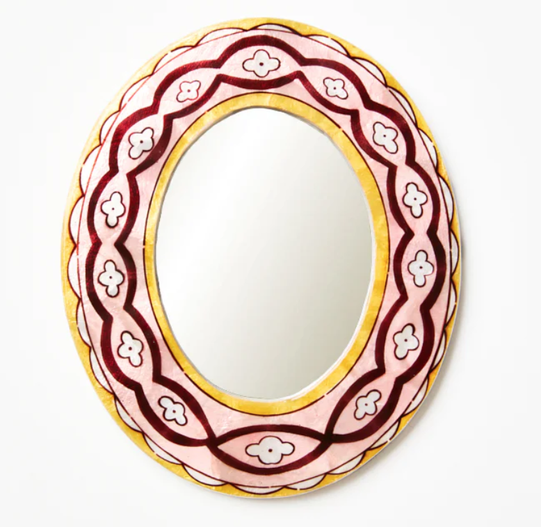 Decorative mirror with a pink and gold frame on a white background