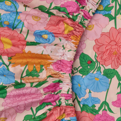Kip & Co - Follow The Sun Organic Cotton Fitted Sheet Close-up of colourful floral sheet with pink, blue, and orange flowers.