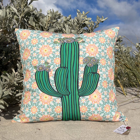 LOST AND FOUND ART CO Saguaro 40cm Cushion Decorative pillow with a cactus design on a floral background, placed outdoors.