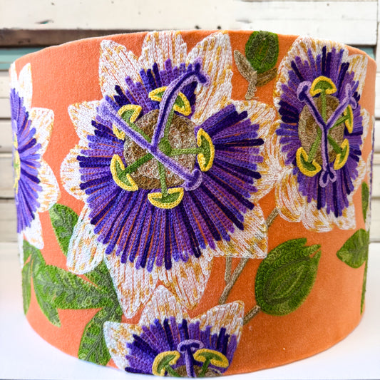 Decorative lampshade with purple floral passionfruit flowers stitched onto an orange velvet background.