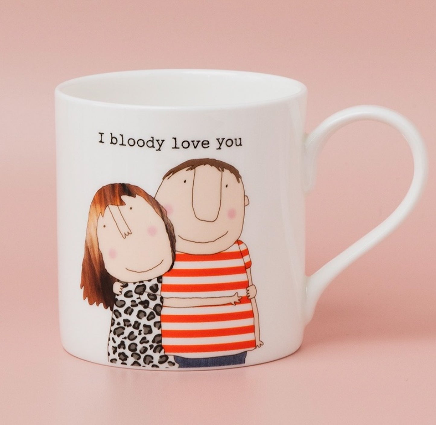 A white ceramic mug with a handle, featuring a cartoon illustration of a couple hugging and the text 'I bloody love you' printed above them, set against a solid pink background.