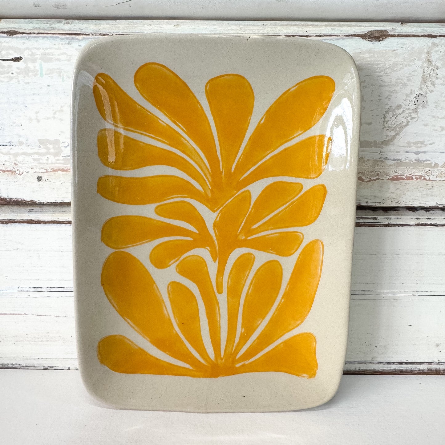 Ceramic tray with yellow floral design on a wooden surface
