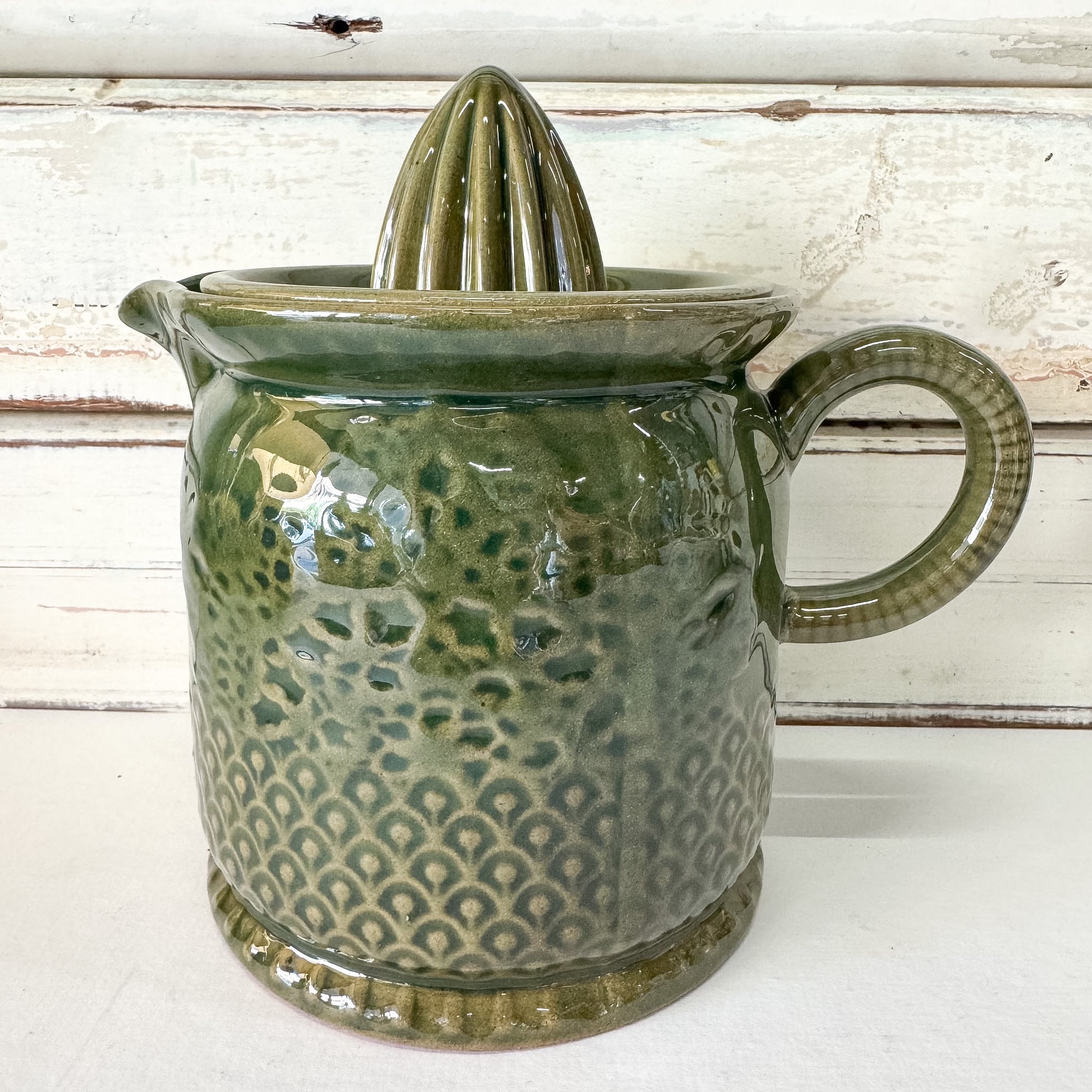 Green ceramic juicer with a textured surface on a white background
