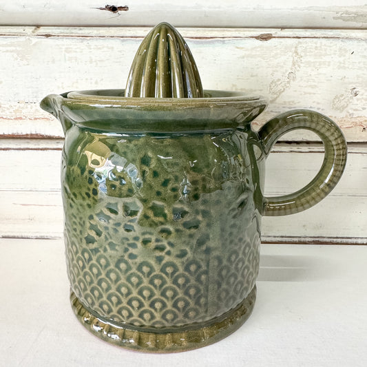 Green ceramic juicer with a textured surface on a white background