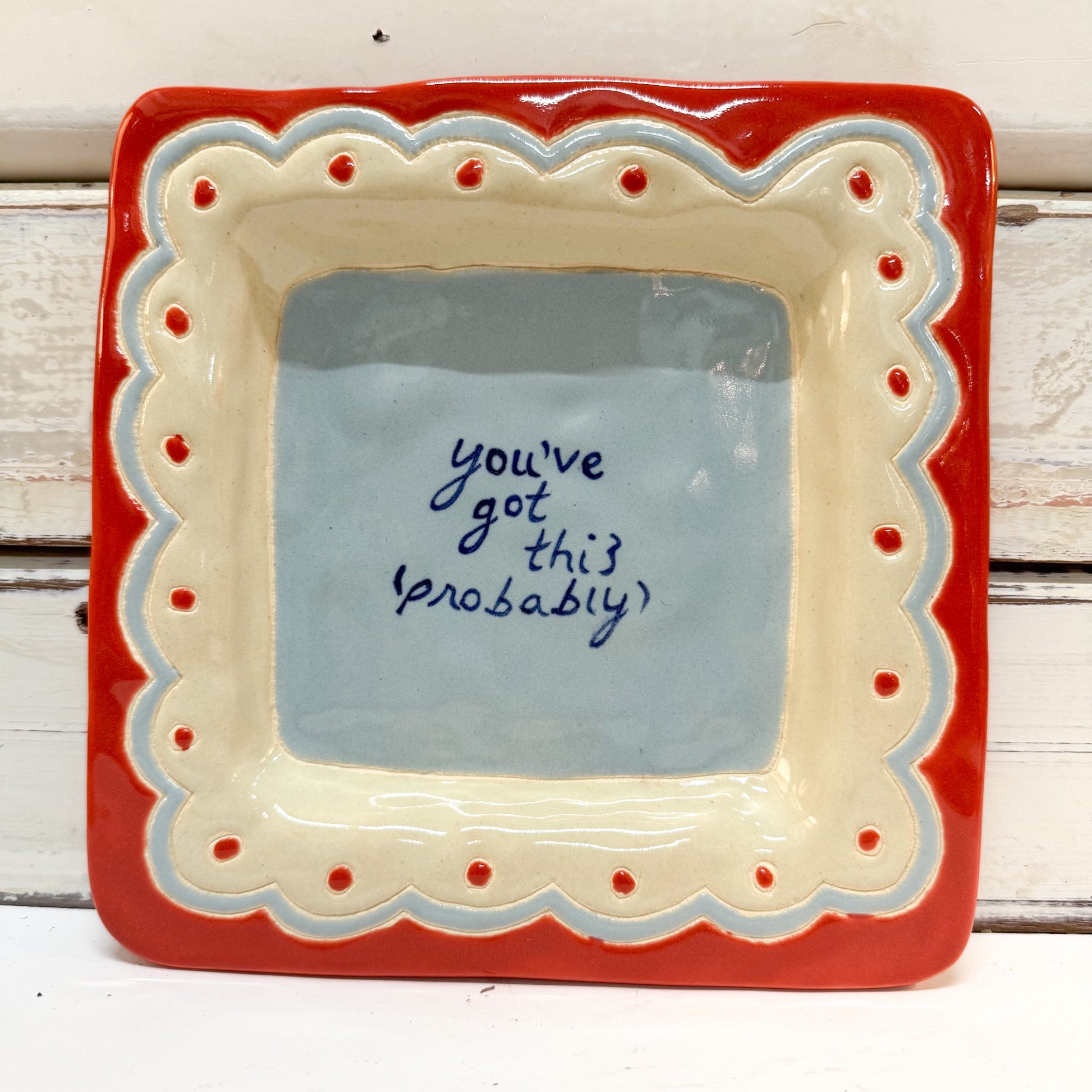 The Brightside Store | Lingo Tray - You Got This A square ceramic dish with a red outer border, cream scalloped inner border, and a light blue center featuring the handwritten phrase 'you've got this probably' in dark blue ink.