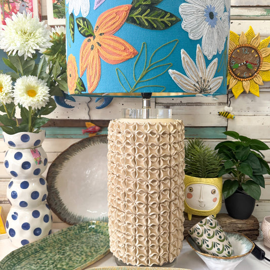 Decorative items including a textured lamp base, floral lampshade, and polka dot vase on a wooden surface.