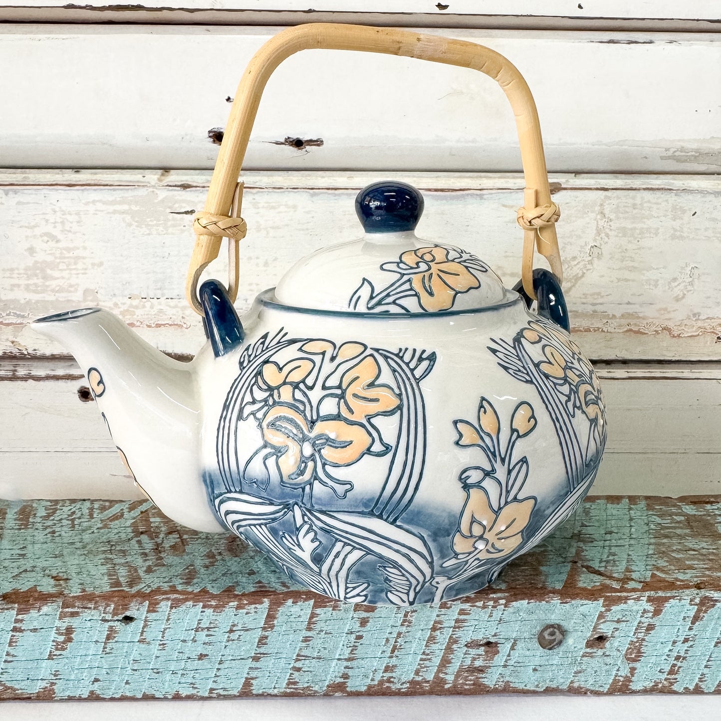 Decorative teapot with floral patterns on a rustic wooden surface