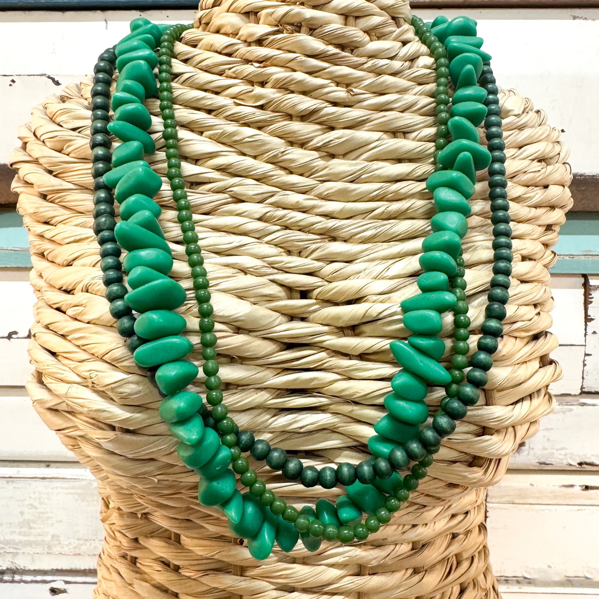 The Brightside Store | Sundaze Necklace ~ Forest Walk A multi-strand necklace featuring vibrant green polished resin & wood dark green beads, displayed on a woven straw mannequin torso.
