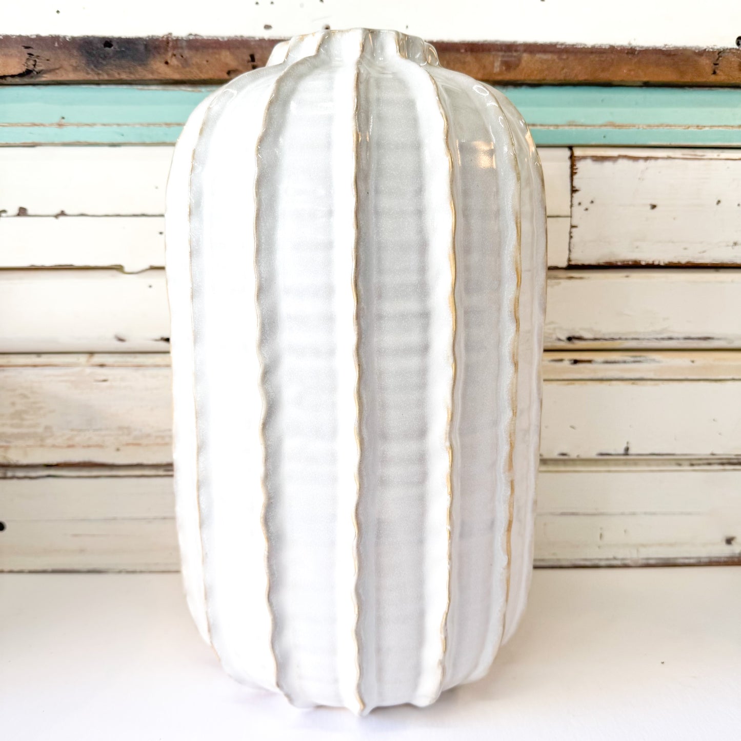 White ceramic vase with ribbed texture on a wooden surface