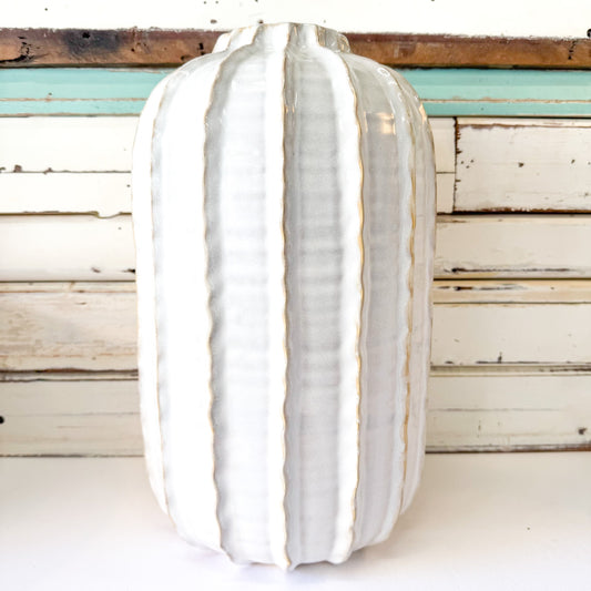 White ceramic vase with ribbed texture on a wooden surface