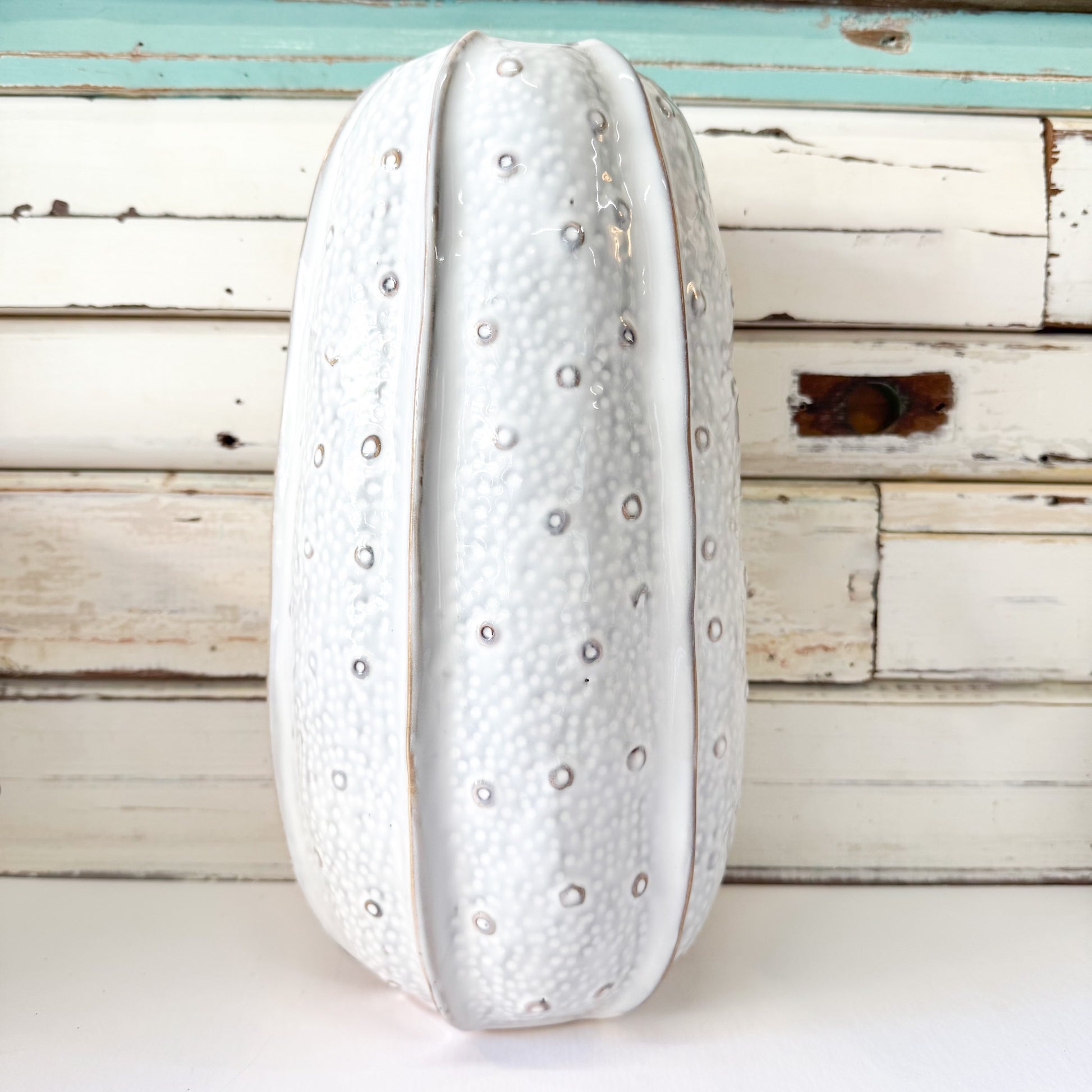 Decorative white vase with textured surface on a wooden background