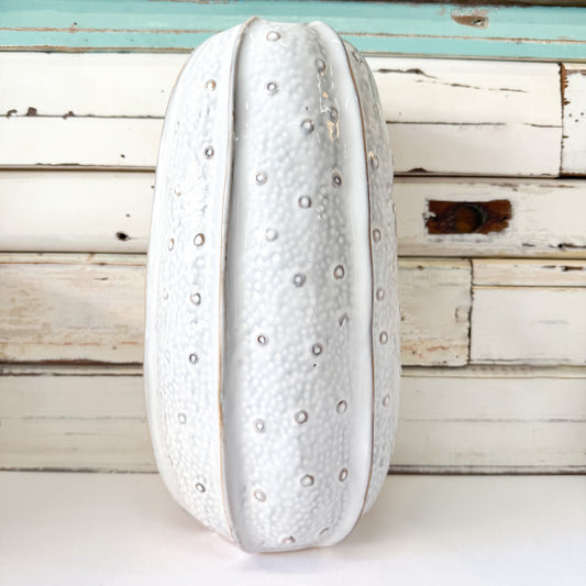 Decorative white vase with textured surface on a wooden background